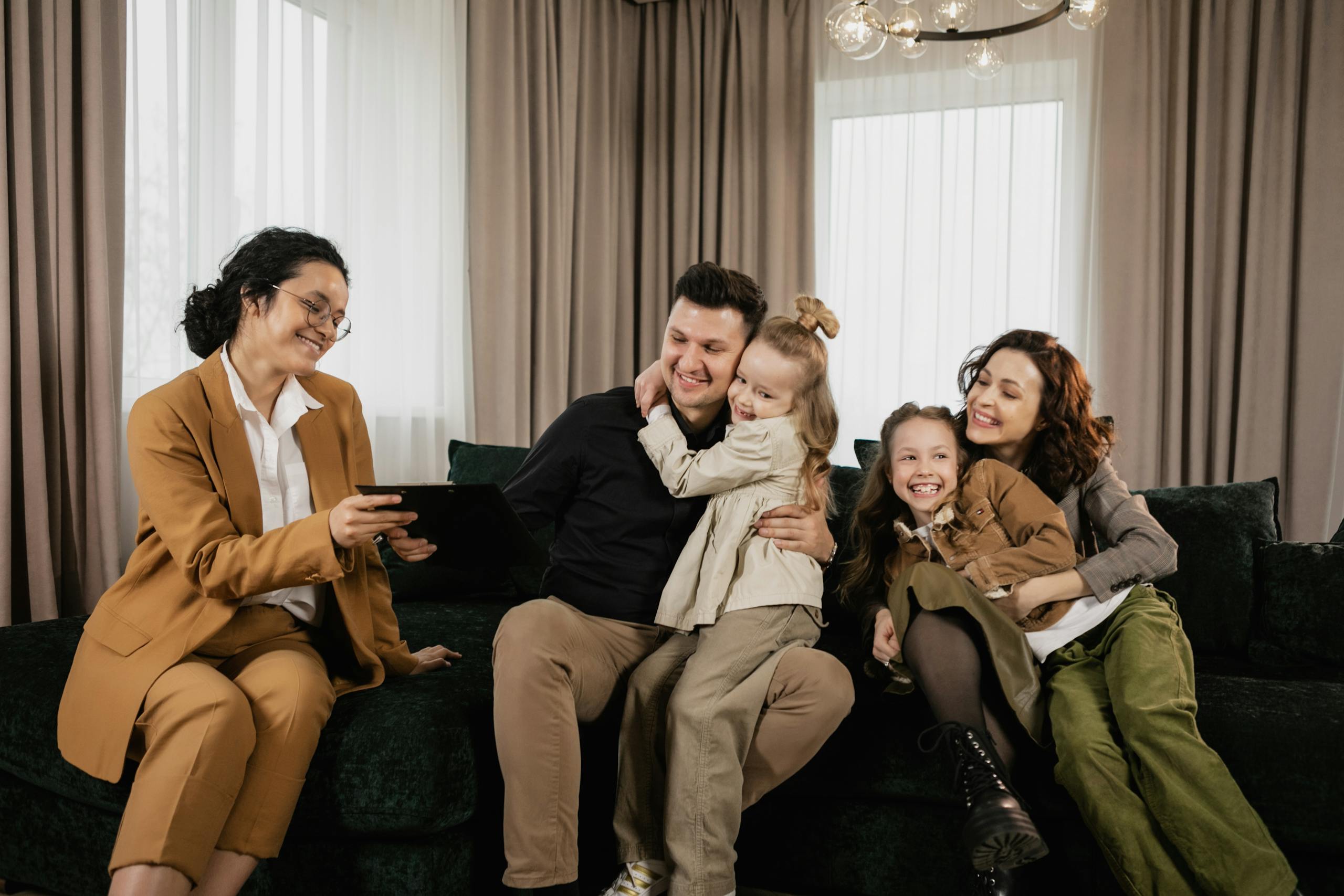 a cheerful family sitting in the living room with a real estate agent discussing a new home purchase 7642018 scaled