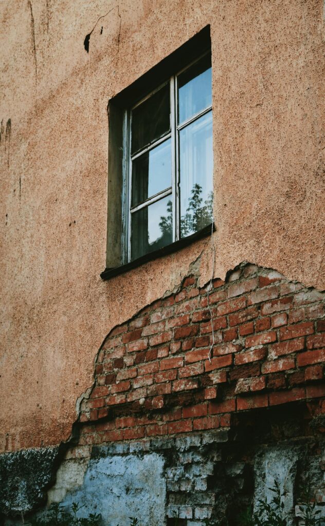 a rustic building facade with a cracked brick wall and single window showing signs of age 27573343 scaled